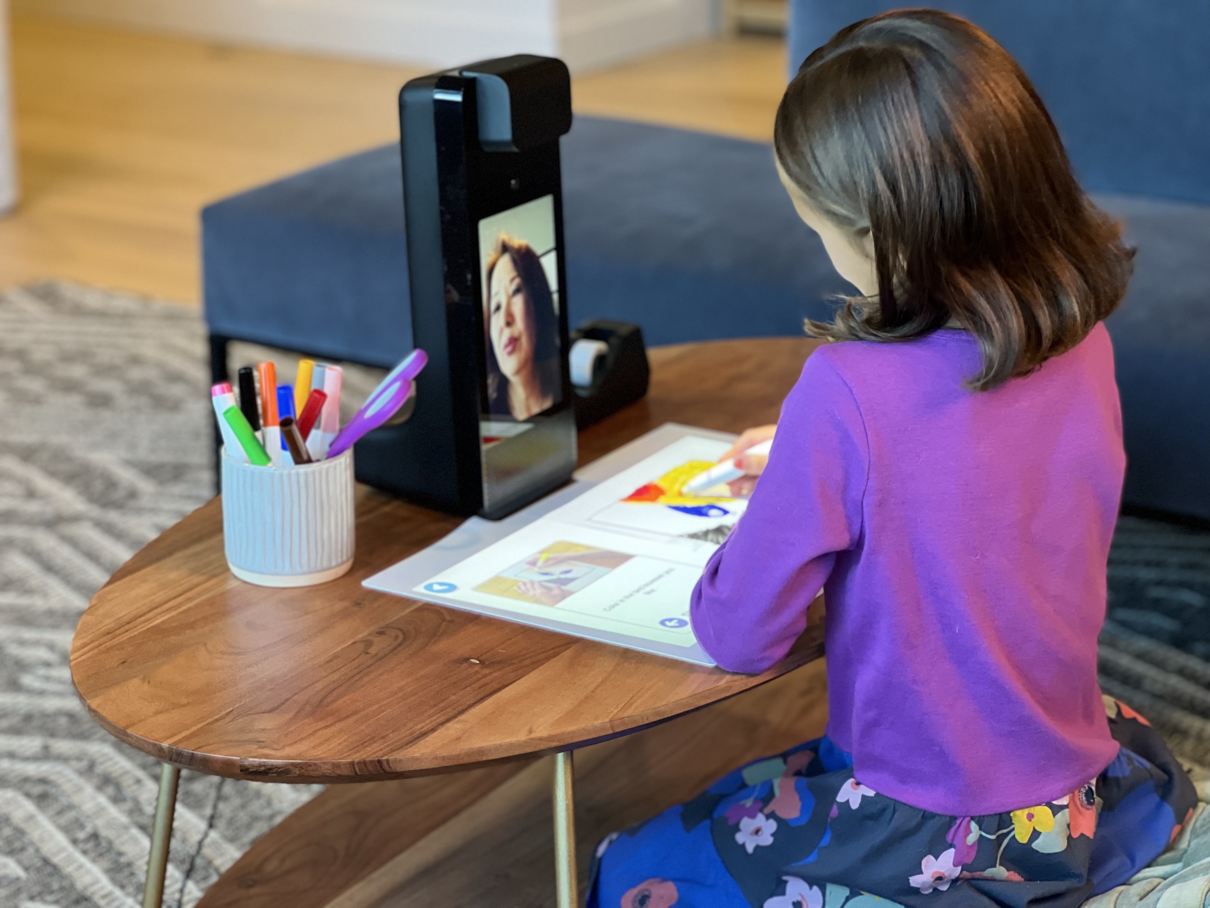 A child colouring on the Amazon Glow's projected touch mat while a remote grandparent watches on the device screen