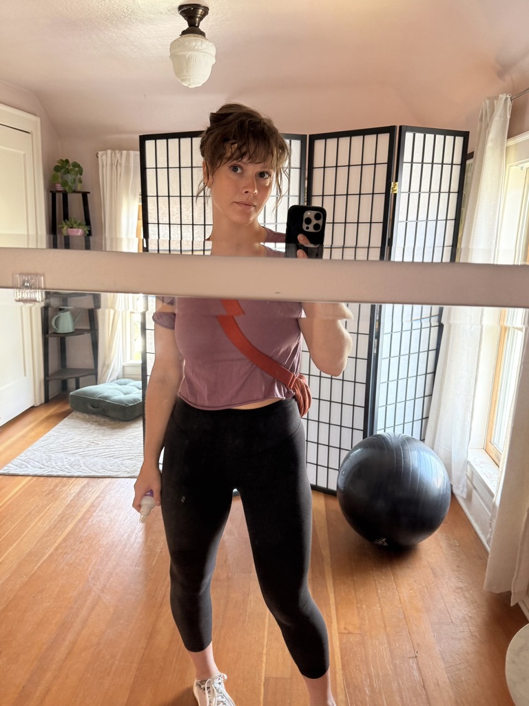 Mirror photograph of a home studio: dusty mauve top, sienna strap, cream walls, honey wood floor and a black shoji screen